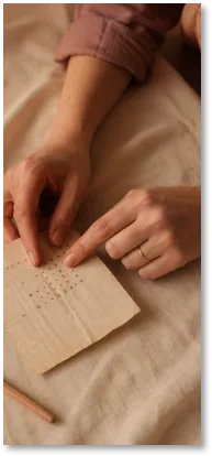 Hands marking a small paper cycle chart on a bed